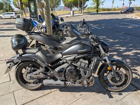 Vista en primer plano de una moto custom Kawasaki Vulcan S 650 con un casco en el asiento trasero, con varias motos estacionadas en Madrid, Espa&ntilde;a, 22 de mayo de 2026