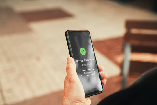 Payment Success Confirmation Screen on Smartphone Outdoors. Online shopping, mobile banking, e-commerce transactions, and digital payment security concept.
