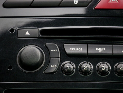 Car audio system control panel with radio buttons and volume knob. Dashboard console interface in vehicle interior. Automotive electronics technology and multimedia equipment equipment.