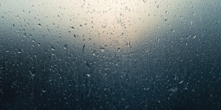Raindrops on a Window Pane at Dusk with Soft Light Background