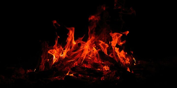 Glowing Campfire Flames Flickering in Darkness with Sparks