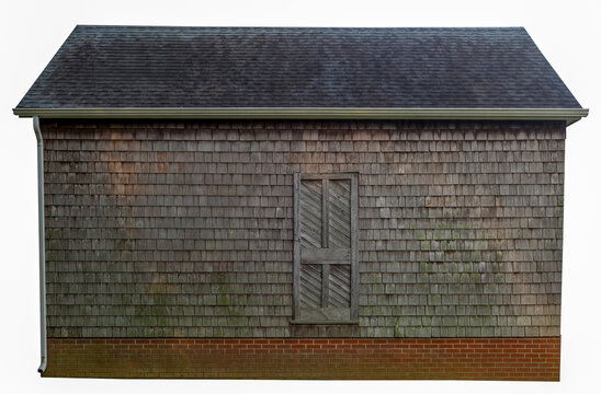 A weathered side wall of an aging wooden building clad in cedar shingles