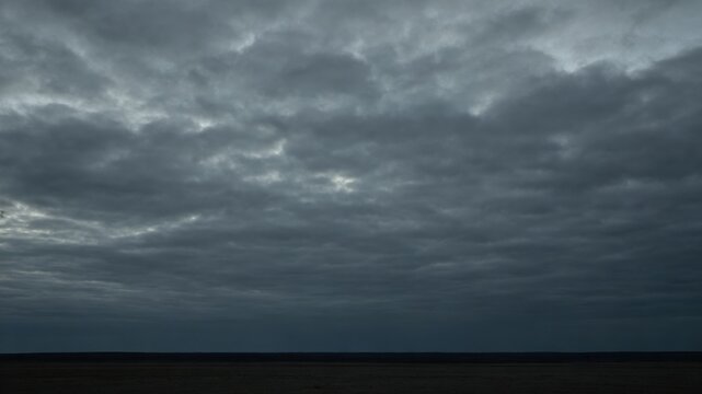 Heavy, overcast sky at dusk with thick gray clouds blocking the sun.