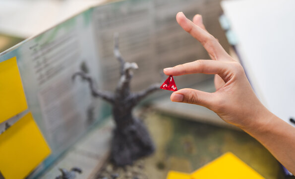 Role playing tabletop game and board games hobby concept. Hand holding dice on blur background with dungeon master screen and adventure story setup ttrpg table.