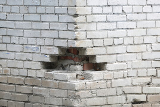 A hole in the corner of a white brick wall