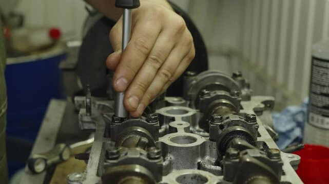 Mechanic tightening car engine cylinder head bolts using a socket wrench.
