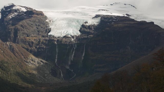 Casta&ntilde;o Overa glacier and cascading waterfalls flowing down a rocky cliff in Nahuel Huapi National Park, Argentina, showcasing glacial ice and mountain water.