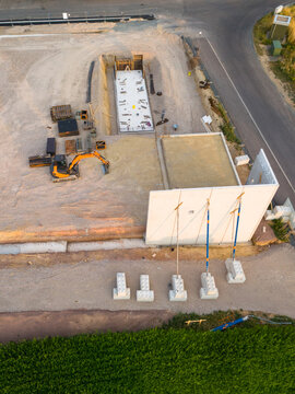 Construction site, foundation for building new supermarket, infrastructure and city development, excavator machine, first standing wall, aerial view