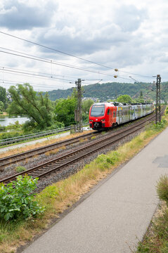 Regional train driving through Moselle valley in Winningen, Germany, railway tracks, modern public transportation, infrastructure in Europe