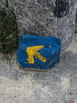 Yellow arrow waymark on blue stone along Camino de Santiago Spain