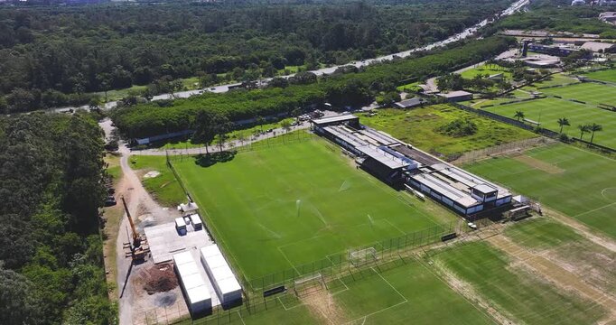 4K aerial drone footage of a professional football training center beside Parque Ecol&oacute;gico do Tiet&ecirc; in S&atilde;o Paulo, Brazil, on a sunny day.