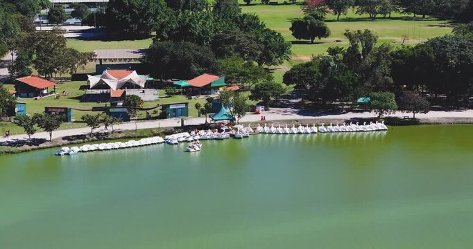 4K aerial drone footage of pedal boats on the lake at Parque Ecol&oacute;gico do Tiet&ecirc; in S&atilde;o Paulo, surrounded by green recreation areas.