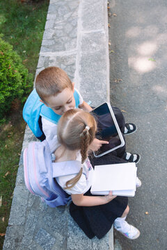 Brother and Sister Using a Tablet Together During a School Break Outdoors