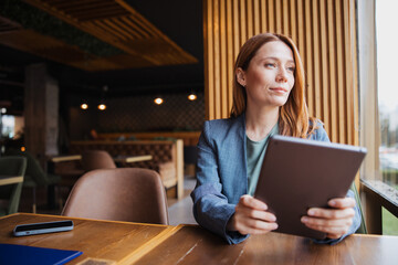 Attractive female professional working on a tablet computer while sitting in a coffee shop © Novak