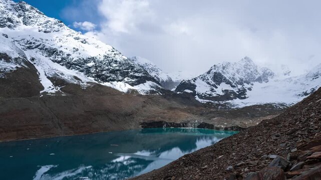 4K Timelapse of Ghepan Lake, snow covered mountains and clouds moving in sky at Lahaul, Himachal Pradesh, India. Natural landscape of India. Travel concept.  High altitude glacial lake in Himalayas.