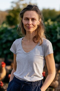 Female farmer portrait smiling gently in organic garden with chickens for sustainable farm profile and background use