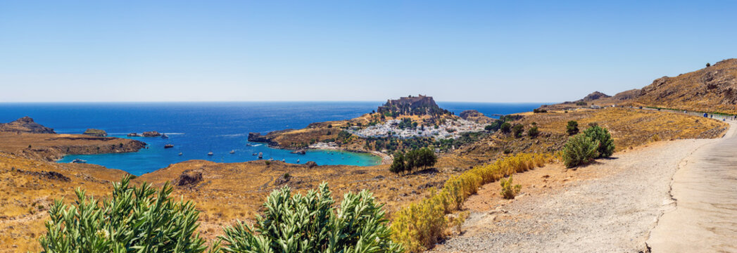 Panoramic coastal view of a scenic bay and white village in Lindos Rhodes under clear blue sky in Greece