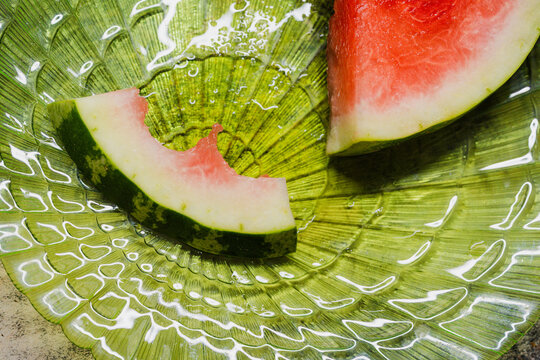 Bitten watermelon slice on a green plate