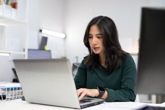 Young businesswoman working on laptop in modern office. Professional using computer for project planning, business management, and workplace productivity.