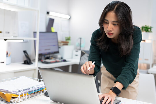 Young businesswoman working on laptop in modern office. Professional using computer for project planning, business management, and workplace productivity.