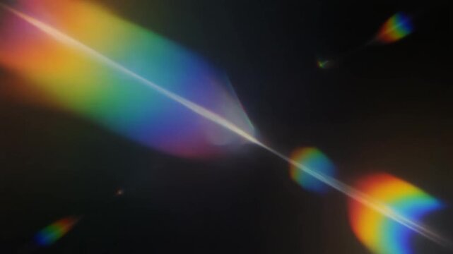 Rainbow lens flare and prism light leaks over dark background. Abstract spectral refraction moving across frame. Cinematic b-roll for creative video overlays and transitions.