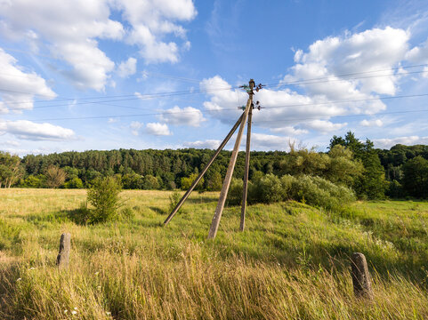 Wooden Utility Pole in Wide Open Field with Forest in Background