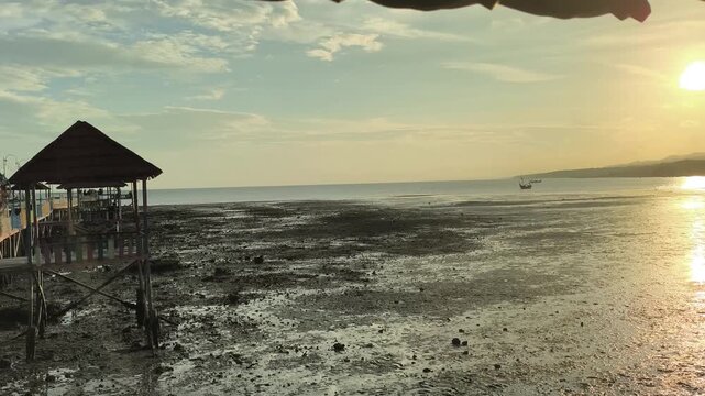Serene coastal view of tropical beach at low tide during golden hour sunset. 4K Video