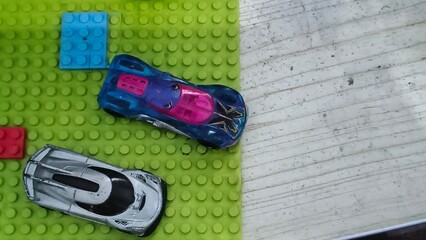 Toy Sports Cars on Green Lego Baseplate with Colorful Bricks © FADEL