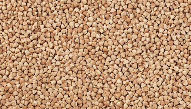 A full frame background, of raw buckwheat, groats, showing a, uniform texture of, triangular brown grains, healthy food ingredient, view, macro