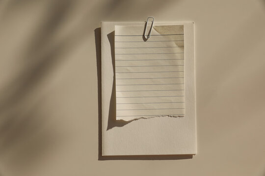Minimal Blank Notebook Mockup with Torn Lined Paper and White Paper Clip. Neutral Beige Stationery Flat Lay with Natural Sunlight Shadows. Elegant Aesthetic Writing Journal Branding Template, Copy