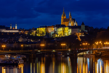 Naklejka premium Illuminated Prague Castle, Strahov Monastery and Vltava River weir at blue hour twilight, Czech Republic