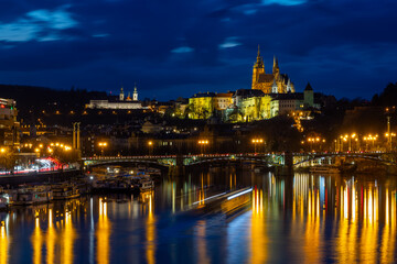 Fototapeta premium Illuminated Prague Castle, Strahov Monastery and Vltava River weir at blue hour twilight, Czech Republic