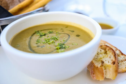 Creamy asparagus soup served with toasted bread on a white plate, highlighting a refined presentation of a classic seasonal dish.
