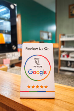 Bangkok, Thailand - 23 July 2026; A review tag with NFC technology inside, using smartphone to tap for review this restaurant on Google. New technology for business working is presented.