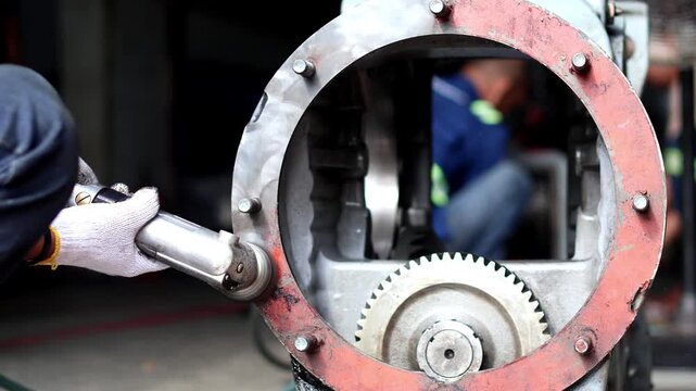 Mechanic grinding metal flange of heavy machinery housing.