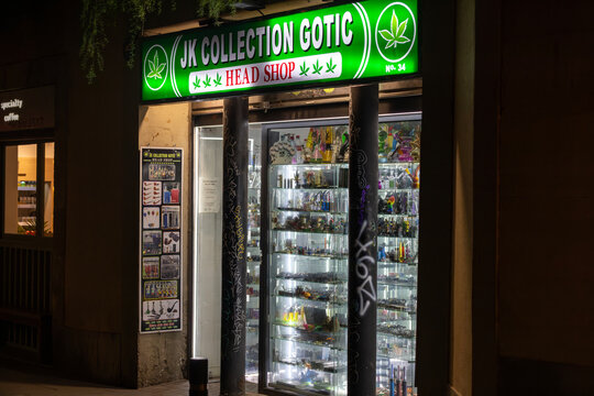 Barcelona, Spain &ndash; January 3, 2026: A brightly lit head shop displays its wares behind a glass window on a quiet street in the Gothic Quarter.