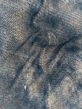 Close up texture of dark fishing net on sand beach