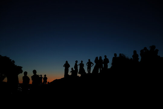 Visitors silhouetted against a deep blue twilight sky on Areopagus Hill in Athens, Greece, a historic site connected with the Apostle Paul's teaching.