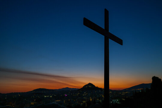 A cross stands silhouetted above Athens, Greece, at sunset on Areopagus Hill, the traditional site associated with the Apostle Paul's famous sermon.