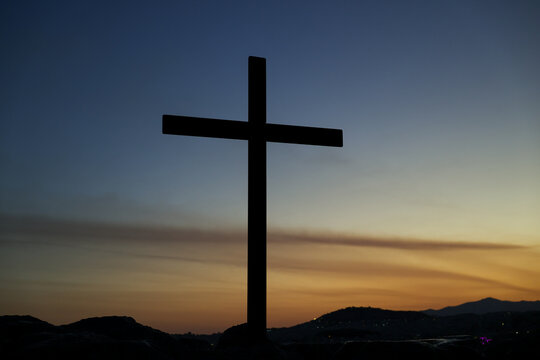 Silhouetted cross on Areopagus Hill overlooking Athens, Greece, against a colorful twilight sky at the traditional site of the Apostle Paul's sermon.