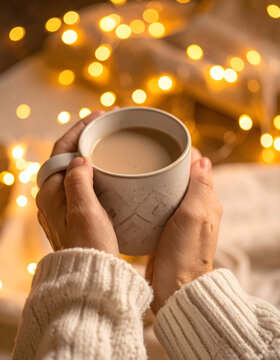 Hands holding steaming mug with blanket and warm fairy light bokeh creating intimate calm mood generative AI