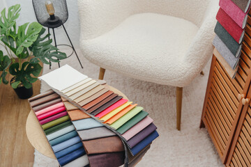 Obraz premium Fabric swatches displayed near a white armchair with a plant