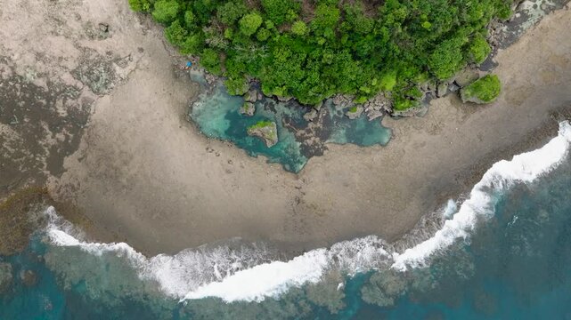 Dense forest meeting rocky shore with tidal pools and breaking waves along the coast. Siargao, Philippines. Magpupungko Tidal Pool.