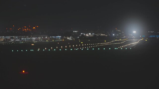 View of an empty airport runway at night with bright approach and edge lights glowing in the dark