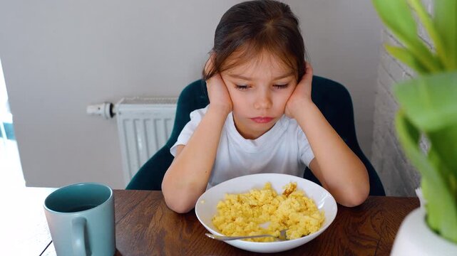 Child lack of appetite. The girl refuses to eat an omelet for breakfast. Child nutrition, healthy eating. The child refuses to eat healthy food. Refusal of proper nutrition. Girl refuses to eat.