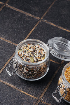 Glass jar filled with mixed seeds on a dark background