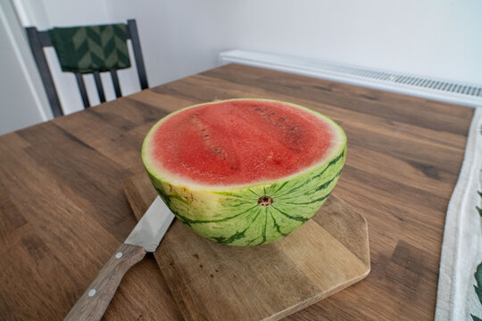 Fresh halved watermelon sits on cutting board close up