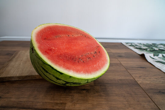 Halved watermelon rests on wooden table by wall