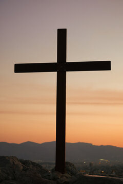 A cross stands on Areopagus Hill in Athens, Greece, silhouetted against a colorful sunset sky at the traditional site associated with the Apostle Paul's sermon.