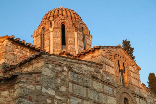 Historic Byzantine church in Athens, Greece, illuminated by warm evening light, showcasing a traditional dome, intricate brickwork, and centuries-old Orthodox architecture.